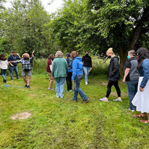 A row of teachers in a nature setting with trees and grass