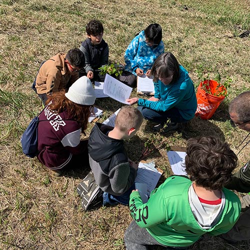 With help from retired wildlife biologist, Julie Nelson, students learn to identify native plants in the local ecosystem before planting some of their own.
